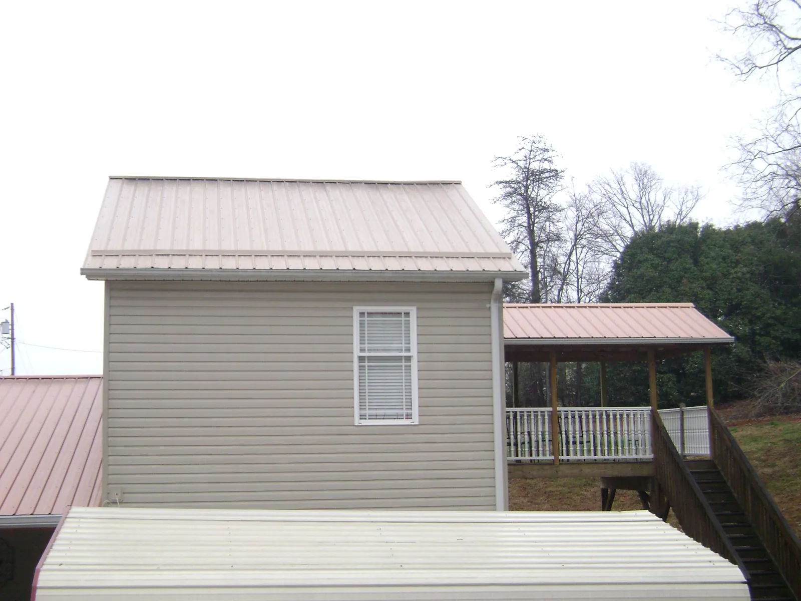 Tan metal roofs on a two story addition and attached porch, from a Roof Replacement job in Upper Marlboro