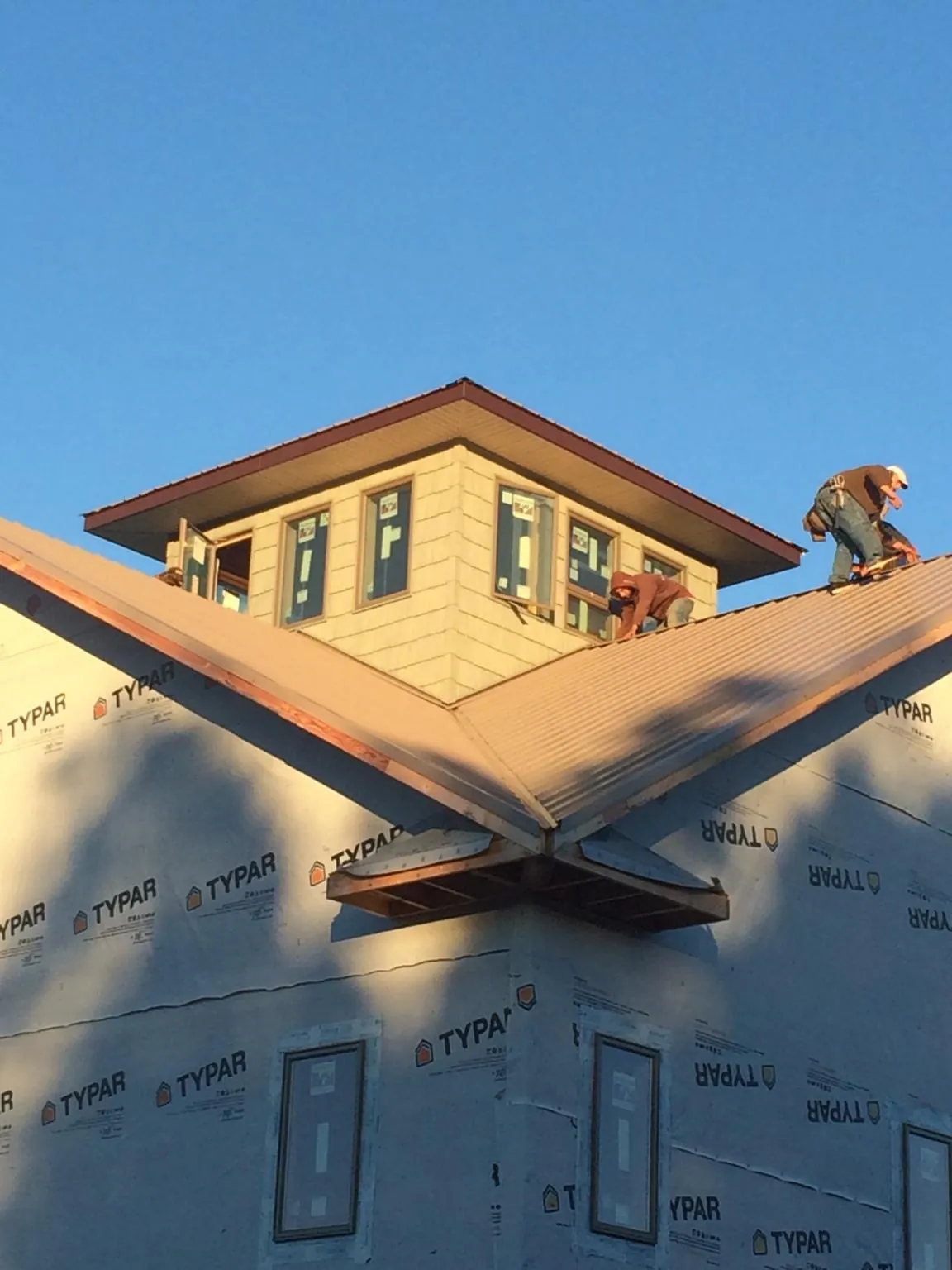 Roofers working around a rooftop cupola on a new metal roof at sunset — Roof Waterproofing in Upper Marlboro by Roofing Brothers
